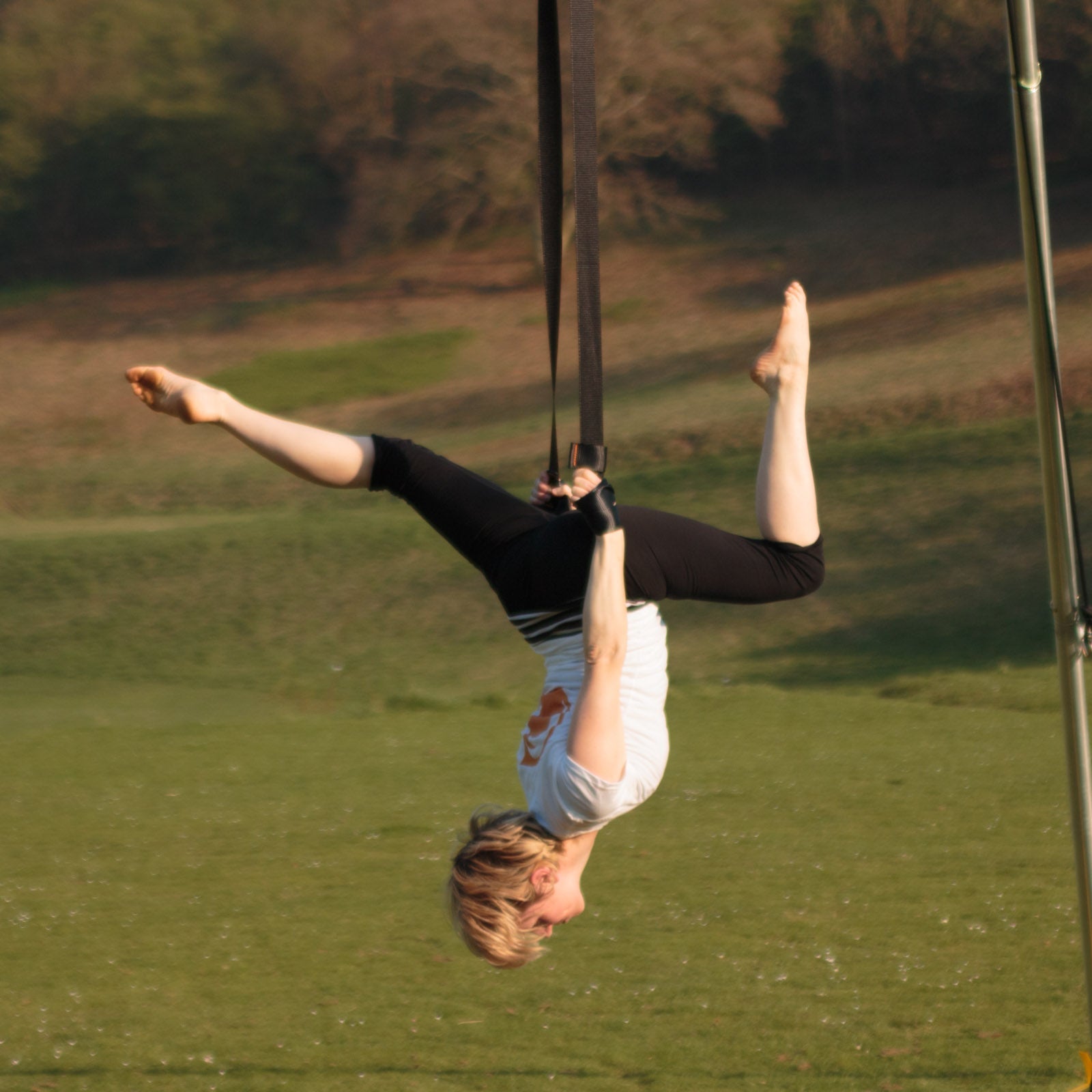 all-groups performer on firetoys aerial straps holding a stag pose upside-down